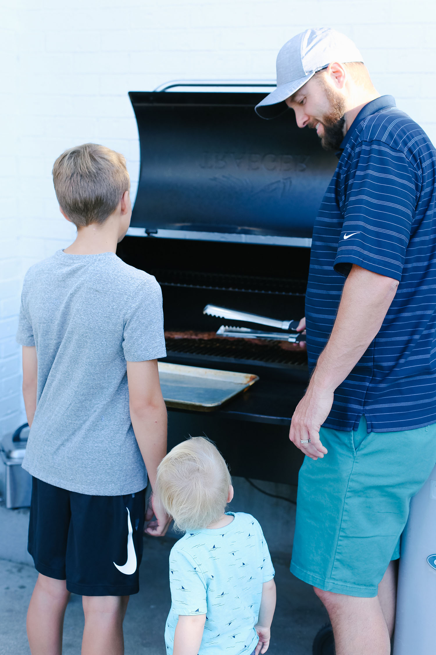 Tips for Hosting a Simple Summer Dinner Party featured by US lifestyle blogger, By Jen Rose: image of a dad grilling with his sons